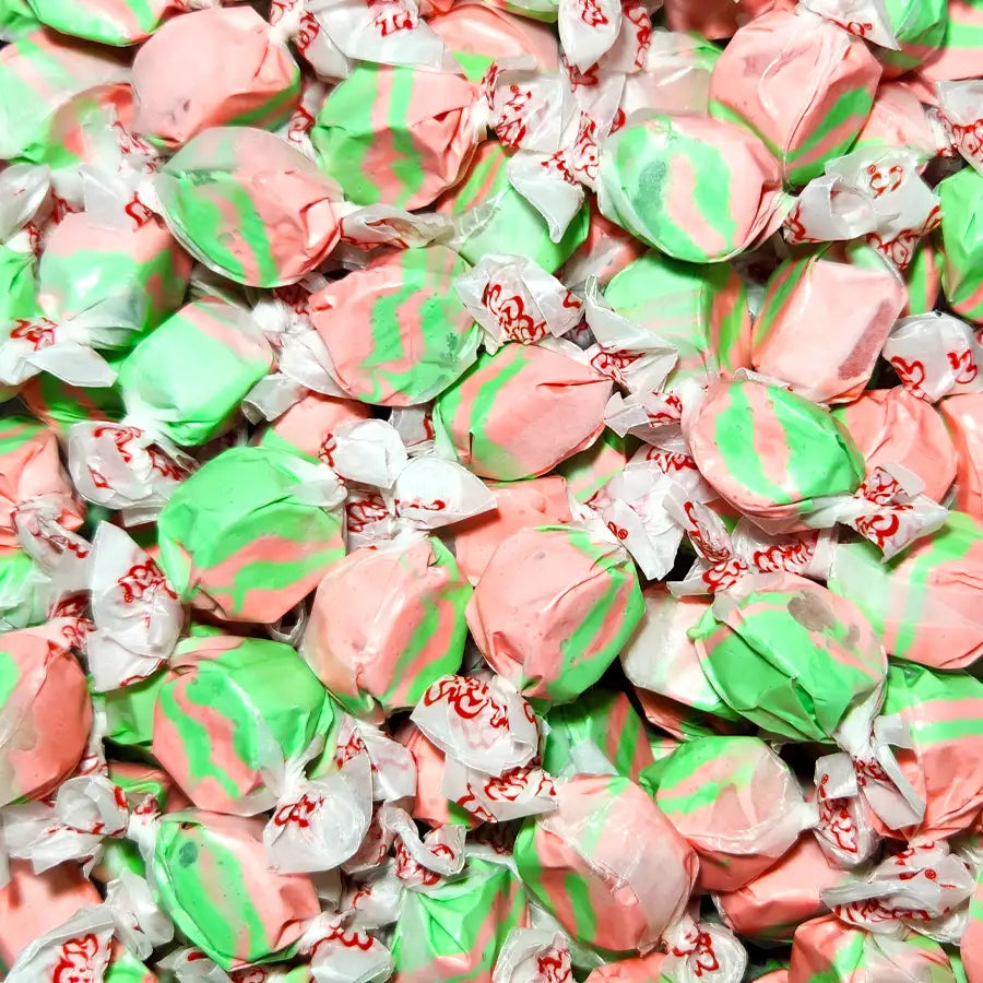 Close-up of pink and green striped candies with white wrappers. Taffy Town Kiwi Strawberry Flavoured Taffy