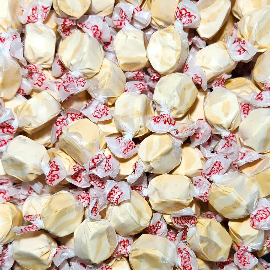 Assorted taffy candies in clear wrappers with red text. Peanut Butter  Flavour
