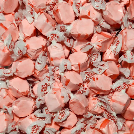 Close-up of pink taffy candies with white wrappers. Strawberry Flavour
